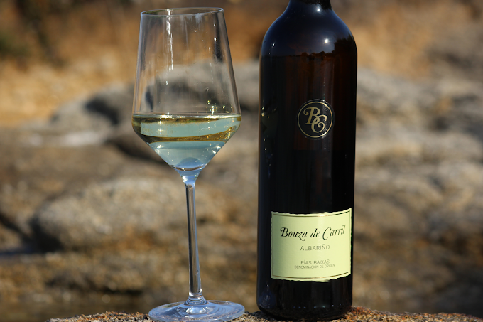 botella de vino de Bodega Bouza de Carril en el viñedo con una copa mediada al lado